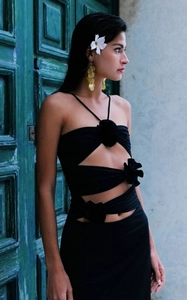 Detail shot of black halter dress featuring 3D floral accents and sexy cutout waist design