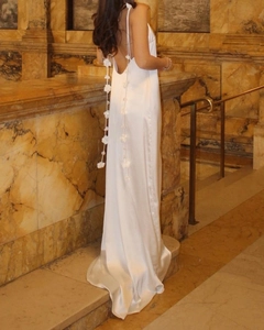 Close-up of elegant white satin backless dress with 3D floral details and silk-like sheen