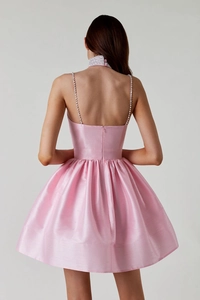 Détail de robe de cocktail en satin rose avec bretelles en cristal et choker strassé