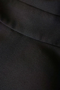 Close-up macro view of black ribbed knit fabric texture showing vertical stripe patterns