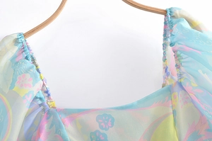 Detailed close-up of elastic square neckline and floral print on light blue chiffon dress