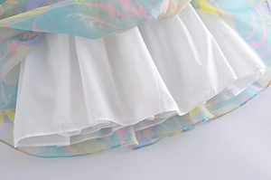 Close-up of floral print mesh dress hem with white pleated lining and gradient scroll patterns