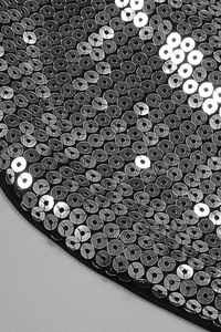 Macro shot of silver sequins neatly sewn on black fabric of this party set outfit