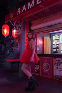Dettaglio dell'abito mini in tulle rosso a balze con allacciatura al collo e neon