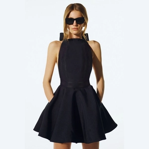 Elegant backless black halter dress with a large bow tie and structured flared skirt
