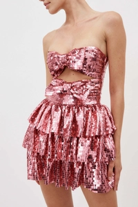 Dettaglio mini abito rosa con paillettes, fiocco decorativo e apertura a rombo