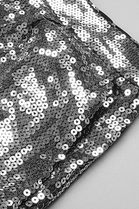 Detail shot of silver sequin fabric showing overlapping metallic textures on evening wear