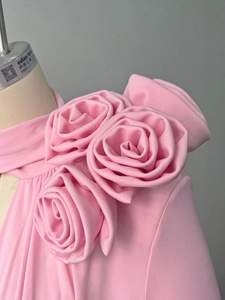 Close-up of pink dress featuring handmade fabric roses and intricate knit texture