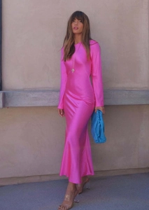 Détail d'une robe satinée rose fuchsia à manches longues avec coupe sirène élégante