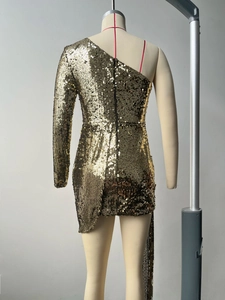 Détail d'une robe dorée à paillettes avec col asymétrique et coupe d'ourlet irrégulière