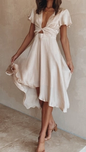 Detail of champagne satin dress featuring deep V-neck, waist cutout, and ruffle sleeves