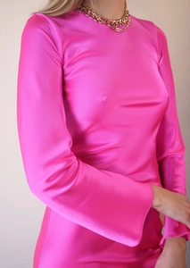 Détail de la texture satinée rose fuchsia et de la chaîne dorée sur l'encolure de la robe