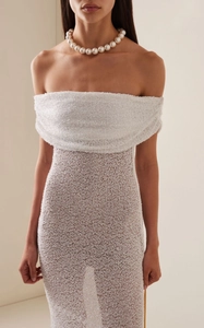 Détail de la robe blanche à paillettes avec design épaules dénudées et texture maille brillante