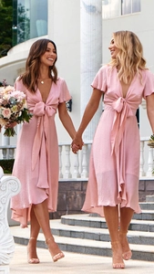 Detail of pink high-low evening dress with deep V-neck and front bow tie detail