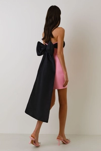 Detail of a pink mini dress featuring a large black silk bow and long trailing ribbons