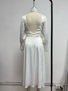 Detail of white satin dress with open back and buttoned cuffs on a mannequin