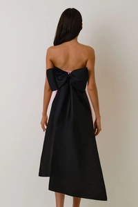 Detail of pink strapless dress featuring a large black bow and asymmetric trailing hem