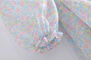 Detail of floral print chiffon sleeve with elastic ruffled cuffs and light pastel patterns