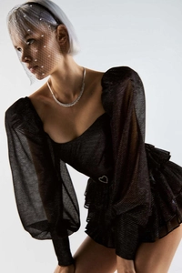 Détail d'une robe noire à manches bouffantes avec texture mesh et accent cœur à la taille