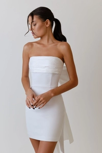 Detail of white strapless mini dress featuring a large decorative bow on the back