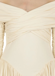 Détail de l'encolure dénudée avec design croisé et fronces sur la robe en tricot crème