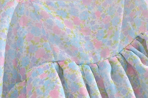 Detailed macro view of floral chiffon fabric with delicate pleats and small pastel blossoms