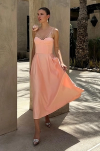 Dettaglio di elegante abito midi rosa con grande rosa in tessuto 3D e spalline sottili