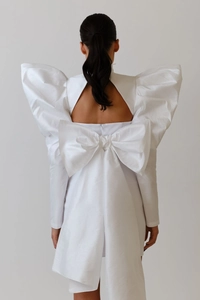 Detailed back view of a white satin dress with puff sleeves and a large bow tie decoration