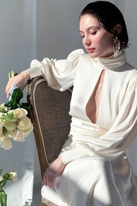 Detail of elegant white satin dress with puff sleeves and cut-out high neck design