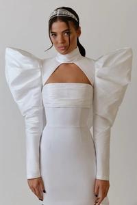Detail of white evening dress with exaggerated puff sleeves and geometric cutout design