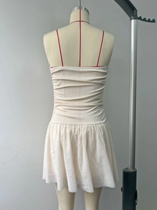 Detail of beige strapless dress featuring ruched knit bodice and pleated skirt hem