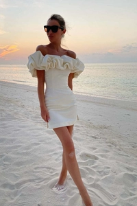 Détail de la robe courte blanche à épaules dénudées avec volants et coucher de soleil