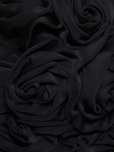 Détail macro de la fleur rose 3D en tissu sur le haut bustier noir sexy ajusté