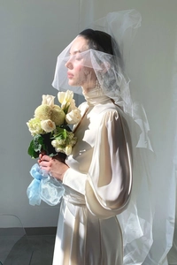 Detail of elegant satin wedding dress with lantern sleeves and floral bouquet