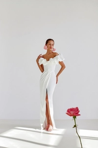 Close-up of elegant white off-shoulder evening dress with ruffled neckline and high slit