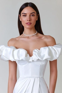 Detail view of ruffled off-shoulder neckline and satin texture of white evening dress