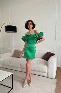 Détail d'une robe en satin vert émeraude à épaules dénudées avec volants et coupe ajustée