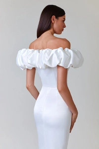 Close-up of white satin off-shoulder evening dress with ruffled neckline and sleek texture