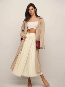 Détail d'une élégante jupe en tulle plissée double couche avec un trench-coat sophistiqué