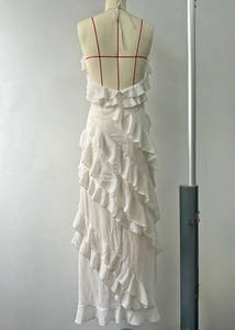 Detail of white ruffled maxi dress featuring an open back and contrasting red straps