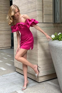 Détail d'une mini robe en satin fuchsia avec volants superposés et épaules dénudées