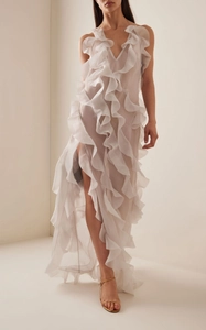 Detail of white tiered ruffle dress featuring deep V-neckline and high slit sheer fabric