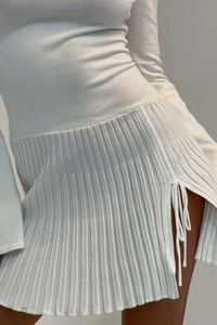 Dettaglio ravvicinato del tessuto a maglia a coste e dello spacco con coulisse sull'abito bianco