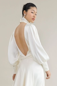 Detail of the backless satin evening gown featuring long puff sleeves and wrap waist