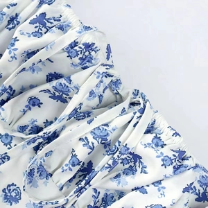 Detail of white floral dress with blue flowers, ruched bodice and elastic smocking design