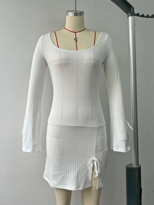 Dettaglio dell'abito in maglia a coste bianco con spacco laterale e coulisse regolabile