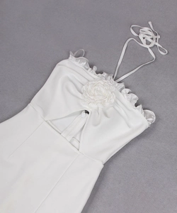 Détail de robe dos nu blanche avec fleur rose 3D et bordures à volants élégantes