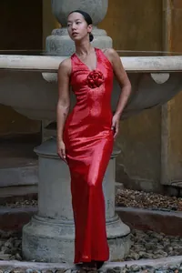 Detailed view of a red sequin evening gown with a 3D floral rose and halter neckline