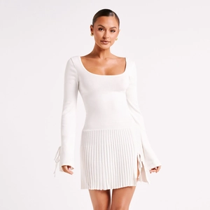 Abito corto in maglia bianca aderente con maniche lunghe allacciate e gonna a pieghe a spacco