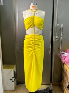Detail of yellow two-piece chiffon set with halter top and high slit maxi skirt on mannequin